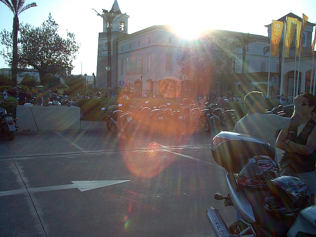 A large car park full of bikes next to a shopping mall in the setting sun